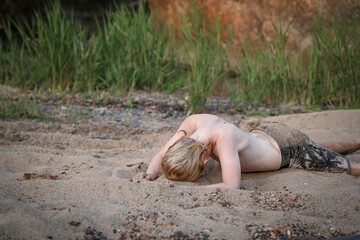 Young boy covered in sand playing on riverbed