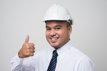 Smiling young asian civil engineer helmet hard hat standing showing thumbs up on isolated white background. Mechanic service concept.