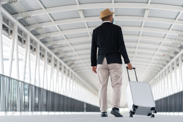 Casual businessman travel with trolley bag walking in the airport terminal. Young man wearing mask arrive to airport. Safety travel concept..