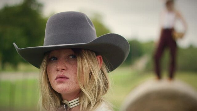 Portrait of a cowgirl looking into camera with a serious expression.