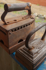 Antique charcoal irons. Vintage irons in row on wooden blue shelf.Old fashioned ironing tools.Heritage concept.