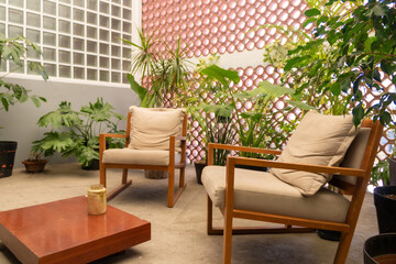 Fototapeta na wymiar Solar. Indoor garden with a variety of plants and white fabric chairs with wood finishes.