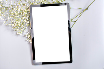 tablet with a place to insert on a gray background next to the white flowers of the gypsophila