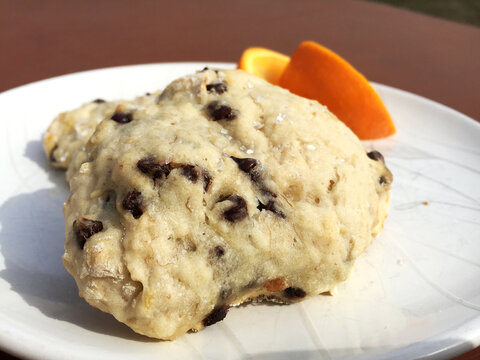 Chocolate Chip Scones with Sugar Crystals and Orange Slices on a White Ceramic Plate