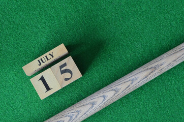 July 15, Number cube with a snooker stick on a green background, snooker table.