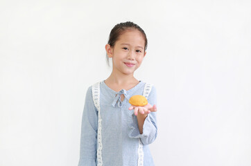 Happy asian little kid girl hold and eating Custard Cake isolated over white background.