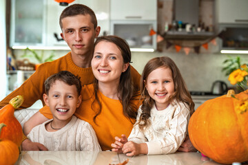 Happy family! mother and her three children sitting at table with pumpkins