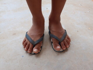 Boy's feet on flip flops standing on the concrete floor