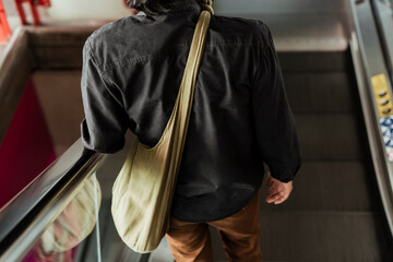 Back view of a man using escalator.