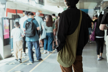 Back view - Asian man waiting for a train on platform.