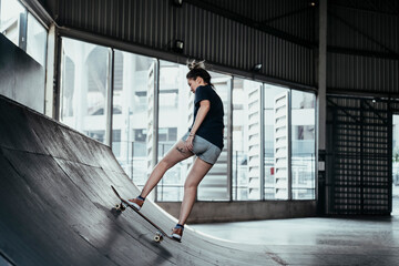 Skateboard player woman rinding board on rusty curve.