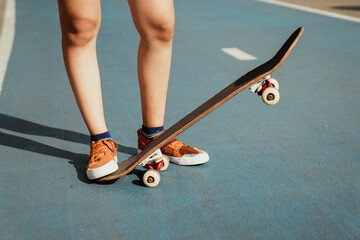 Legs of woman stand on skateboard.
