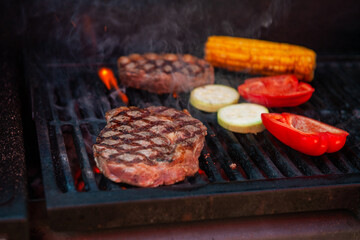 Beef steaks with vegetables on the grill with flames