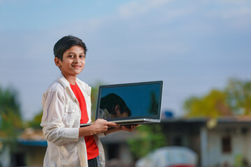 Cute little Indian/Asian boy studying or playing game with laptop computer