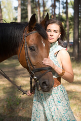 Young beautiful woman walking in the forest with her horse	