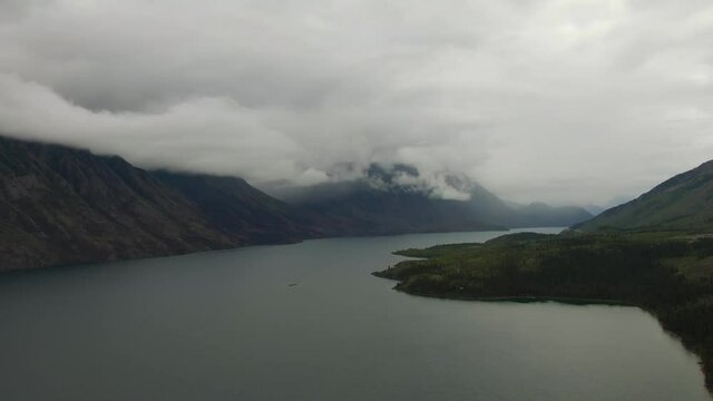 Beautiful View of Scenic Lake surrounded by Mountains and Trees on a Cloudy Day. Aerial Drone Shot. Southern Yukon, Canada.