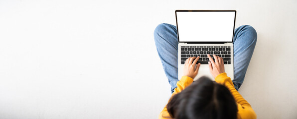 Top view of woman sitting on floor and using laptop blank screen white background. Mockup, template for your text, Clipping paths included for device screen. Panoramic image with empty copy space - obrazy, fototapety, plakaty