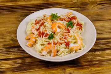 Spaghetti pasta with prawns, tomato sauce and parsley on wooden table