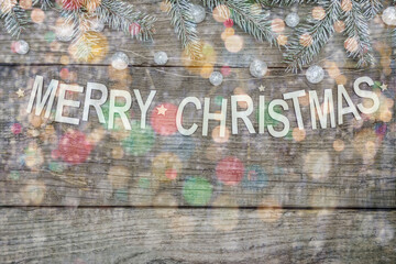 rustic wooden background decorated with snowy fir tree branches, garlands and merry christmas lettering