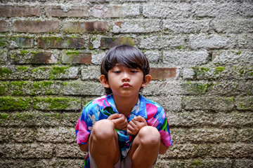 Asian Little Boy with Sad or Bored Expression. Rustic Brick Walls Background