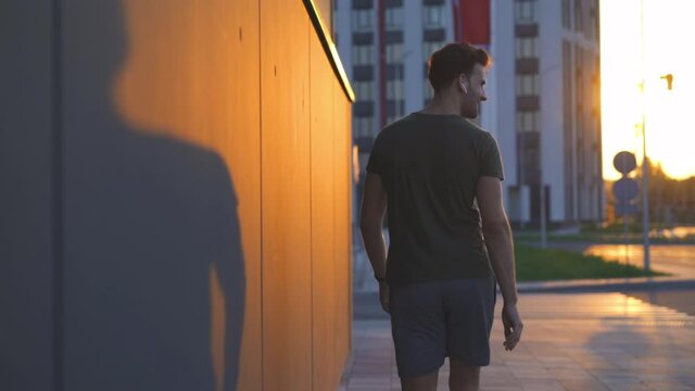 The attractive man walking and using airpods. slow motion