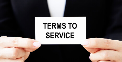 The businessman holds a business card with the text OF TERMS TO SERVICE.