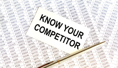Obraz premium The card shows the text KNOW YOUR COMPETITOR, next to the pen. Background - accounting reports.