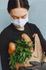Girl in a medical mask. Woman holds a bag of groceries during an epidemic. The concept of food during quarantine. Coromavirus theme.
