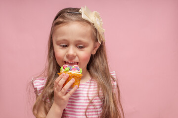 Cute little girl eating a cake on a pink background