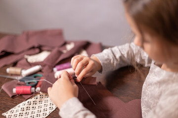happy cute little girl is engaged in sewing home