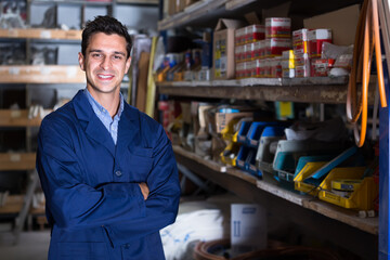 Fototapeta premium Portrait of cheerful working male in uniform on his workplace in building store.