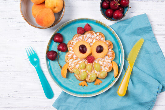 Waffle with fruits and berries in the shape of cute owl with balloons, food for kids idea, top view