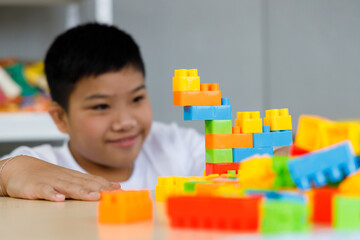 Asian boy play colorful brick toys during free time.