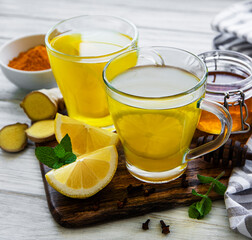 Energy tonic drink with turmeric, ginger, lemon and honey on a white wooden background