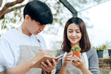 Women hold cactus and a man writing note in a book. Love couple enjoy hobby with darden cactus.