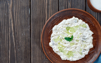Ali nazik meze, a traditional Turkish dish of yoghurt and eggplant puree topped with a mint leaf. Side dish for kebab in a clay plate on a wooden background with spear space. Flat lay