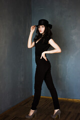 Fashion girl model posing on blue background. Ypung woman with long black hair and hat