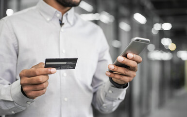 Man hand holding credit card and using smart phone at office closeup. Businessman or entrepreneur working. Online shopping, e-commerce, internet banking, spending money concept