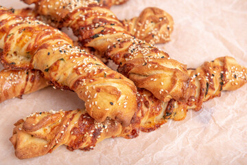 twisted puff pastry sticks on white paper parchment, wood table
