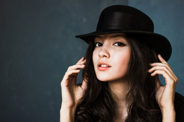 Portrait of beautiful brunette woman in hat, stylish girl posing on blue background