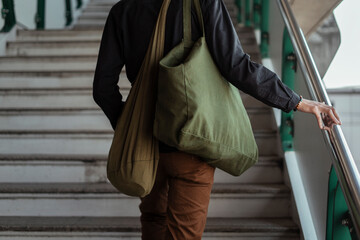 A man with canvas bag walking up stair.