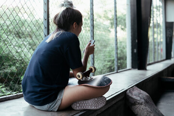 Skateboard woman player using smartphone.