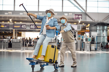 Fototapeta premium Male pensioner wheeling his wife on a baggage trolley
