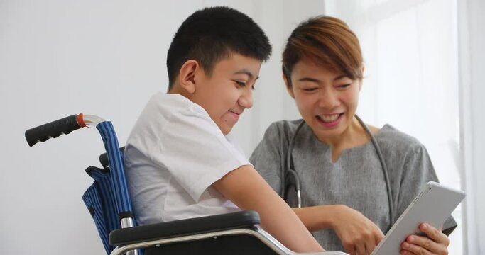 A physical therapist is talking to a disabled boy in a wheelchair.
