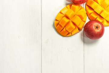 ripe mango and apples on white wooden background