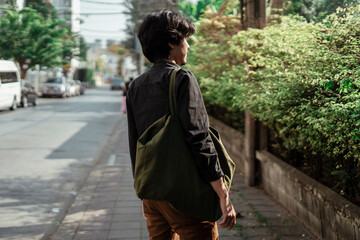 Man carrying a canvas bag walking on street.