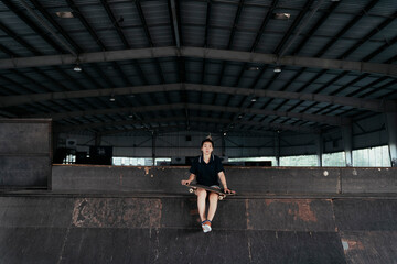 Skateboard player woman sitting with a board.