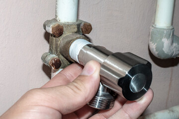 A man installs a distribution pipe fitting with a shut-off valve for the water supply. The master...
