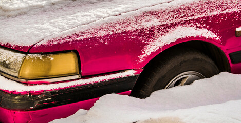 Car closeup. Fragment. Old car under the snow. Abandoned. Winter snow. Pink