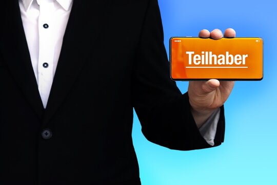 Teilhaber. Anwalt (Mann) zeigt ein Handy. Auf Display steht Text. Hintergrund blau. Hand h&auml;lt Telefon.